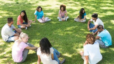 Photo of a young people sitting in a circle on the lawn